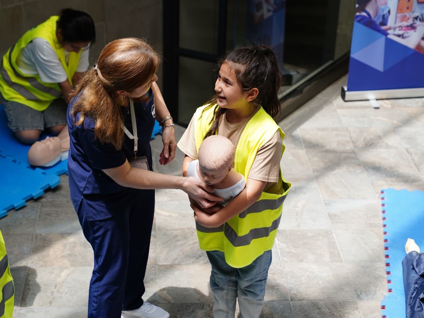 Instructor guiding a child through infant CPR on a pediatric training mannequin
